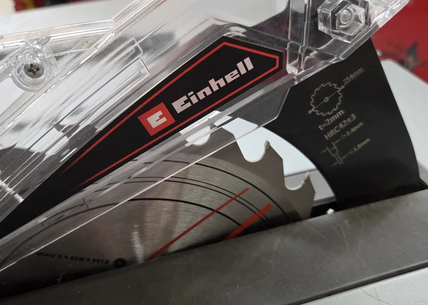 Nahaufnahme des metallischen Sägeblatts mit 254 Millimeter Durchmesser unter einer transparenten Schutzhaube mit rotem Einhell-Schriftzug.